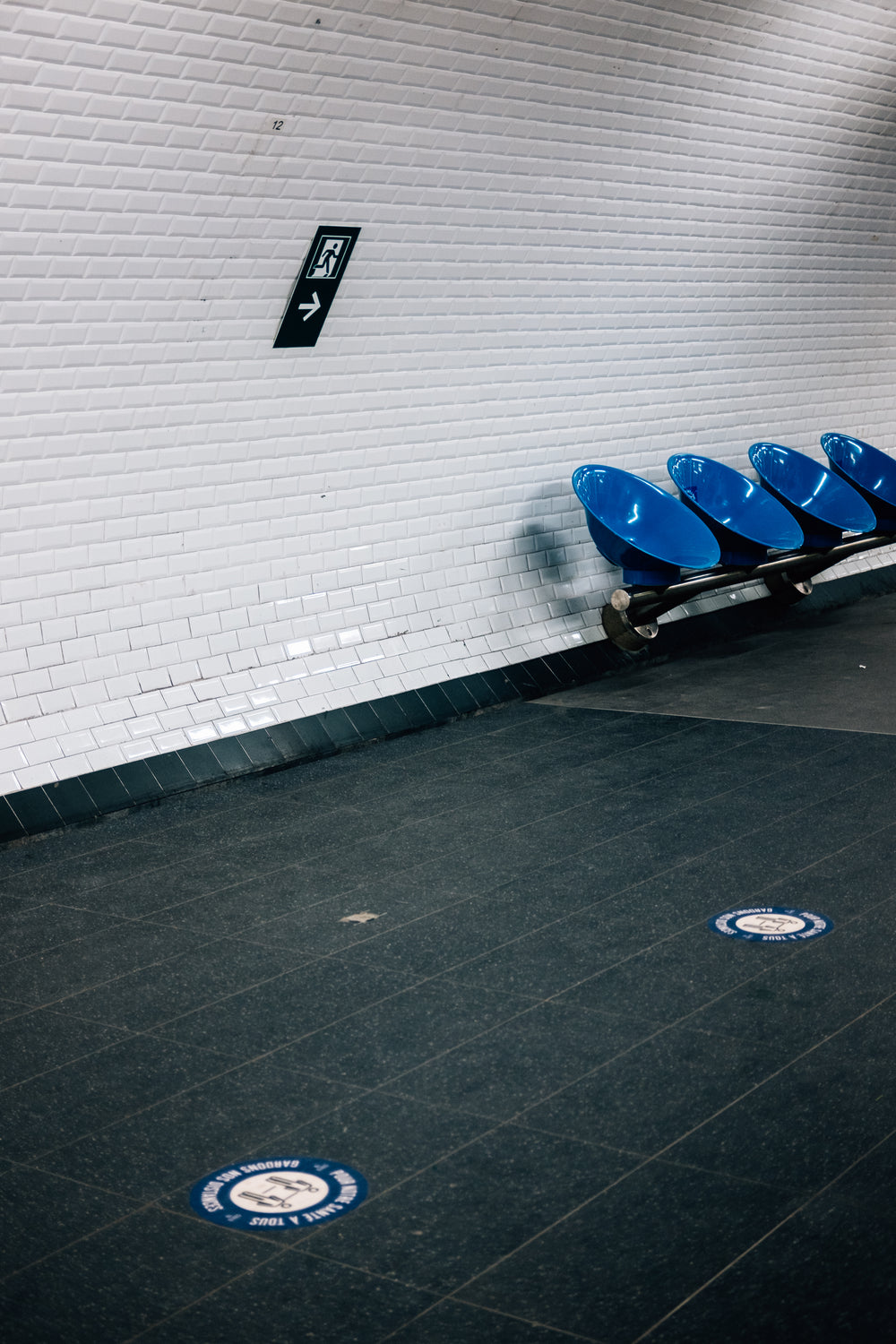 white tiles wall and round blue chairs