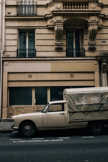 white truck parked outside a tall beige building