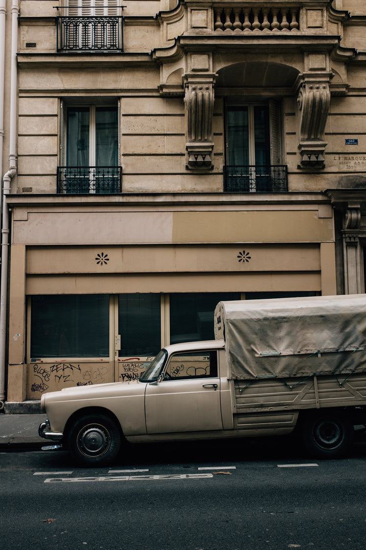 White Truck Parked Outside A Tall Beige Building