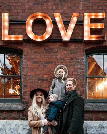 a brightly lit sign spells out the word love and a family is