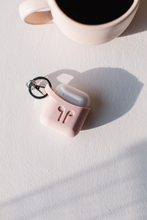 wireless earbuds in a pink case lay on a table