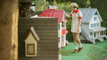 woman and dollhouse with red roof