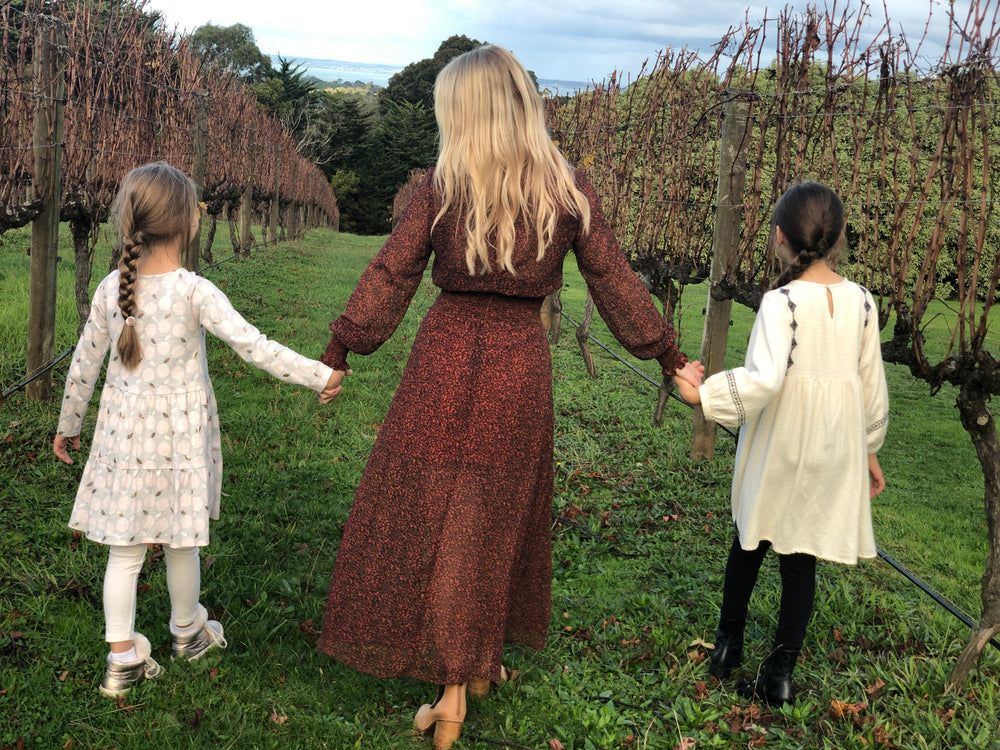 woman and girls walk grassy path