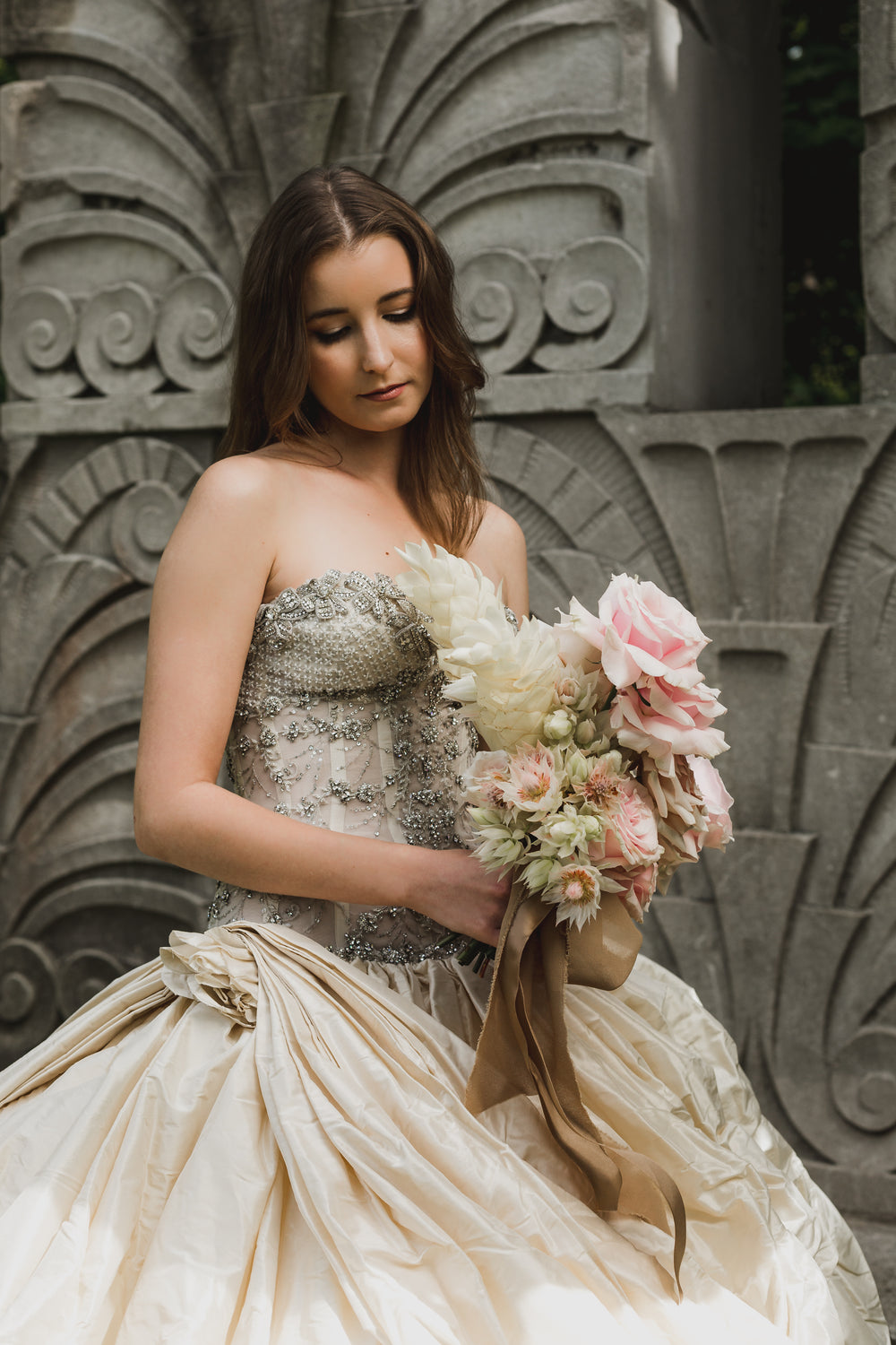 woman bride holding flowers in front of stone wall