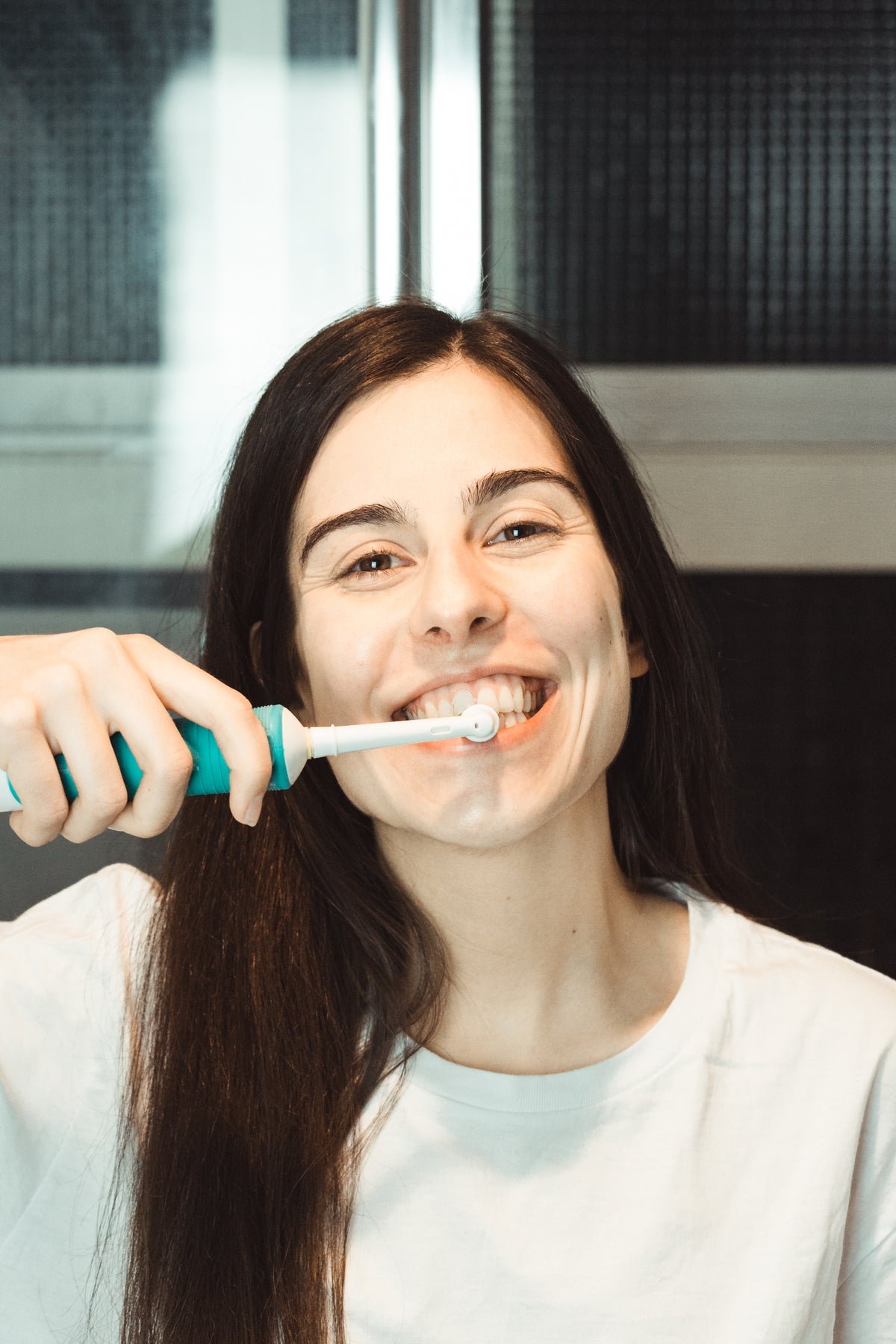 woman brushes her teeth with an electric toothbrush
