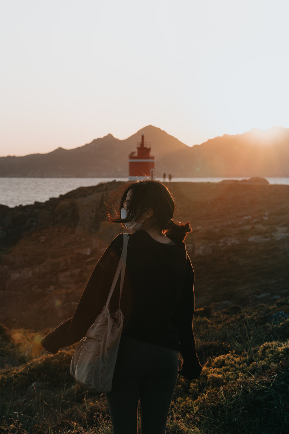 woman carries a bag and walks down towards the water