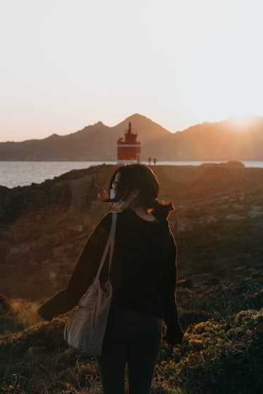 woman carries a bag and walks down towards the water