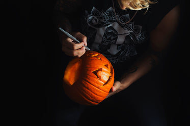 woman carves a smiling jack o lantern