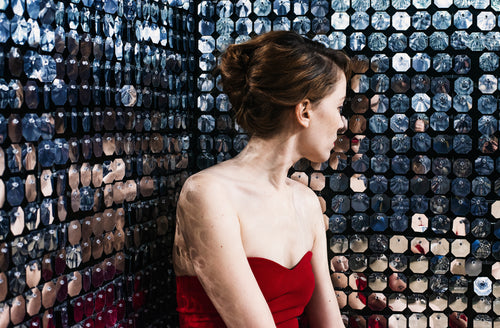woman catches her reflection in a wall of mirrors