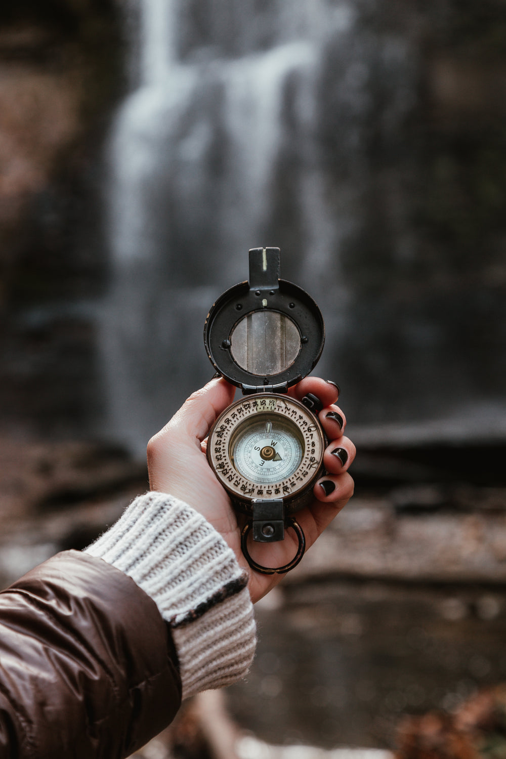 woman checks compass at waterfall