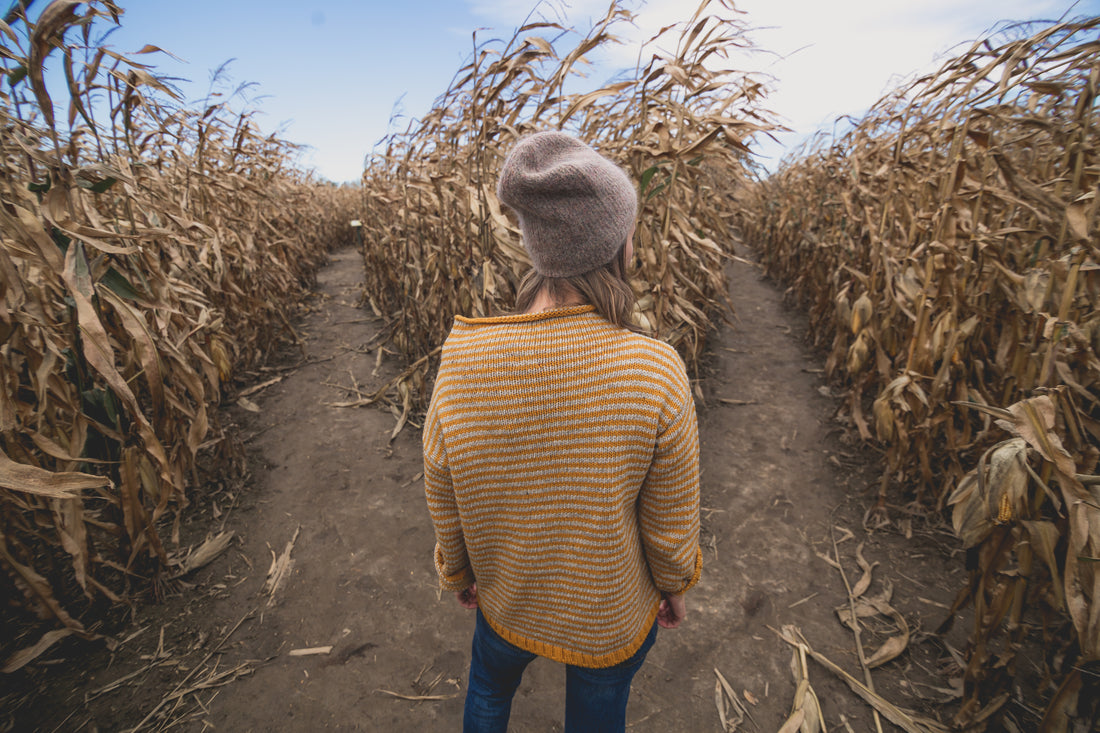 A woman pausing at a fork in a hedged path