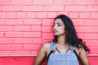 woman close up leaning against pink wall