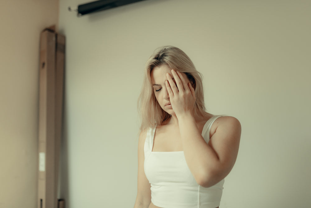 woman closes her eyes and holds a hand to her face