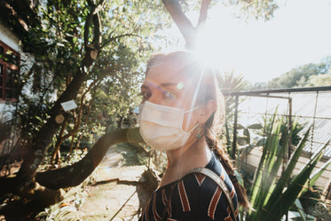 woman covering face with mask on a green pathway