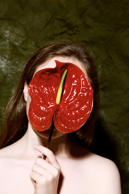 woman covering her face with anthurium blossom