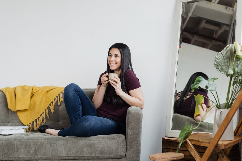 woman cradles coffee on a sofa