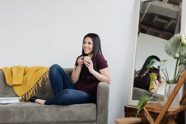 woman cradles coffee on a sofa