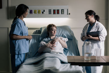 woman cradles newborn baby under watchful eyes of doctors