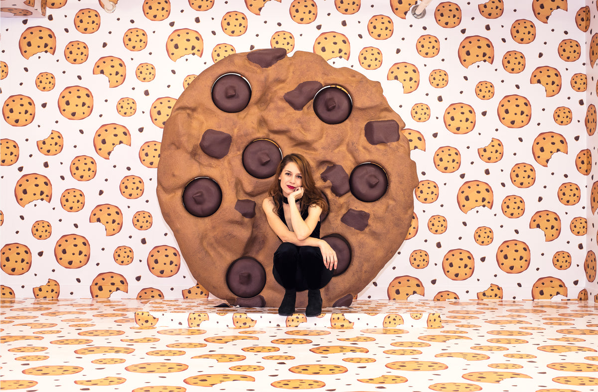 woman crouched down in front of giant cookie display