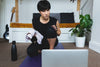 woman crouching in front of laptop holding a white towel