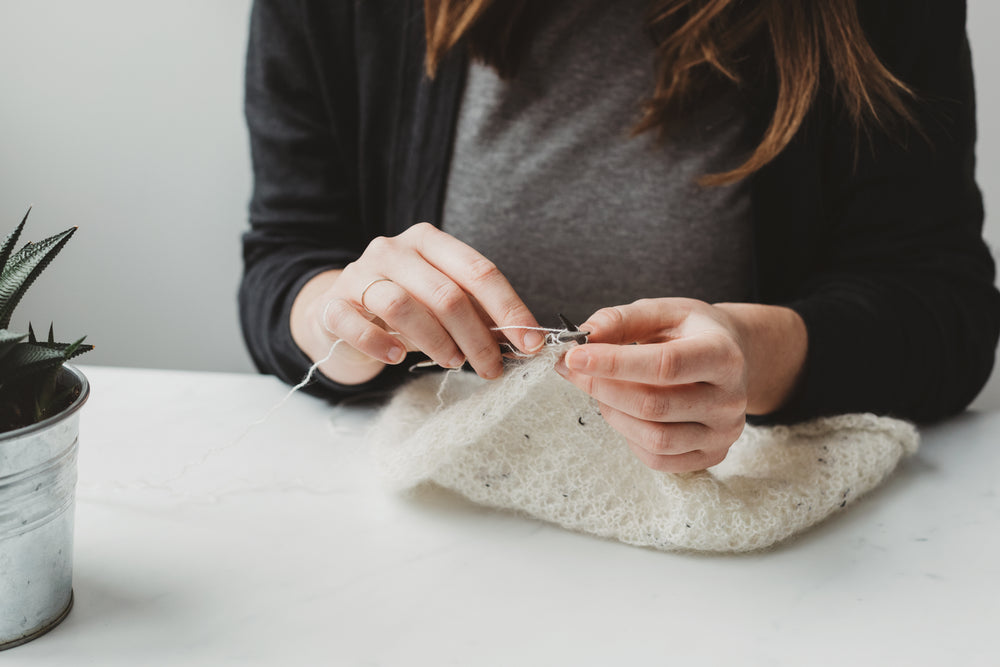 woman deftly knits white yarn