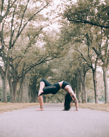 woman does bridge pose yoga on path