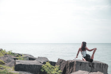 woman does yoga by the water