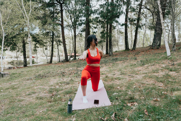 woman does yoga on a pink yoga mat outdoors