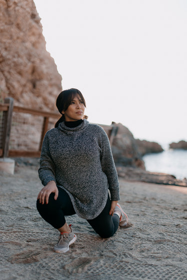 woman does yoga stretches on a beach in the morning light