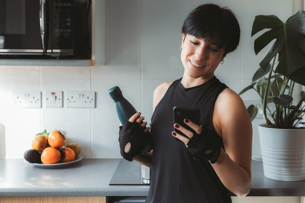 woman dressed for a home workout looks at her cellphone