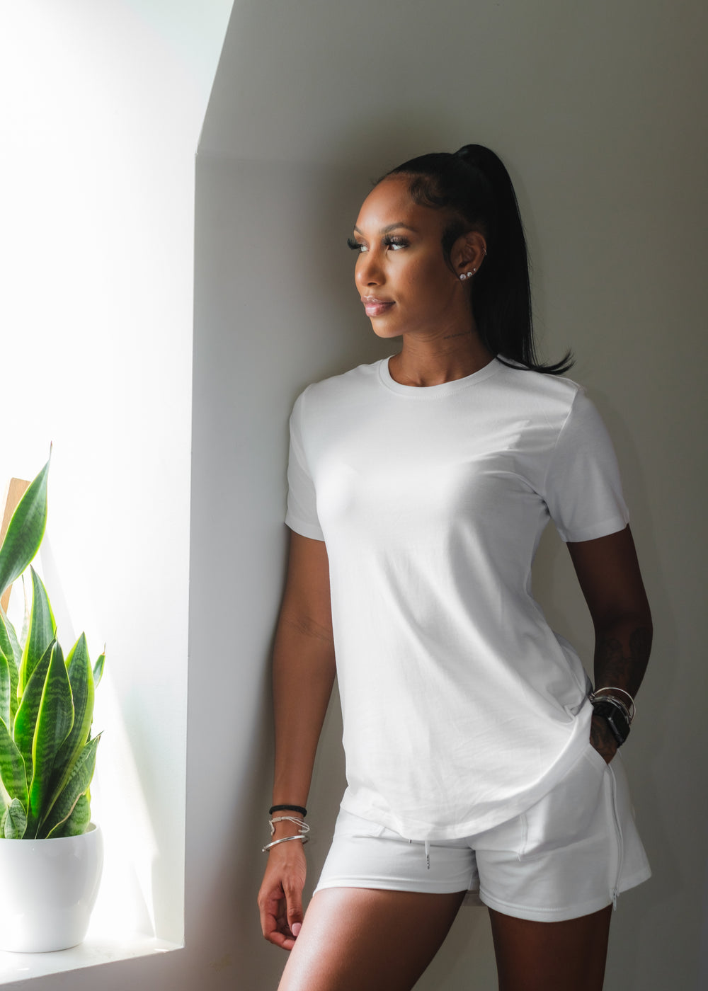  woman dressed in white leans against a wall