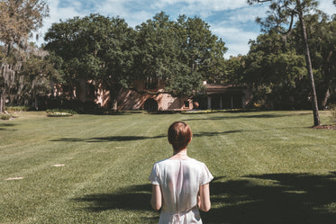 woman dressed in white linen looks across lush florida park