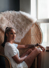 woman dressed in white t shirt in a wicker peacock chair