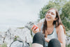 woman eats an apple outdoors and laughs