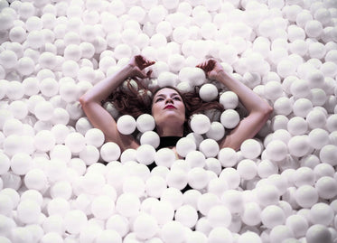 woman floating with arms raised in ball pit