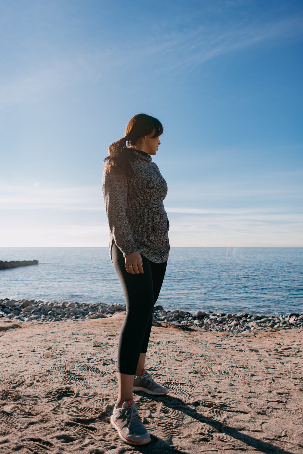 woman glances back at the sea behind her in the morning light