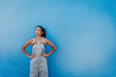 woman glasses hands on hip blue wall