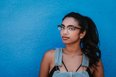 woman glasses ponytail blue wall