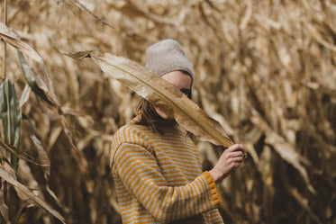 woman hides behind dry harvest leaves