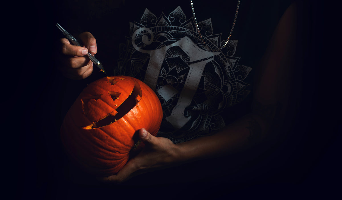 woman holding a scalpel carves a pumpkin
