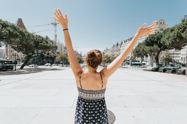 woman holding her hands up above her head in a courtyard