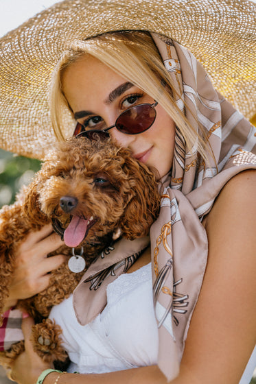 woman holds a small brown puppy close outdoors