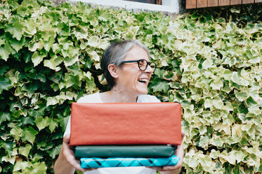 woman holds a stack of gifts and smiles wide