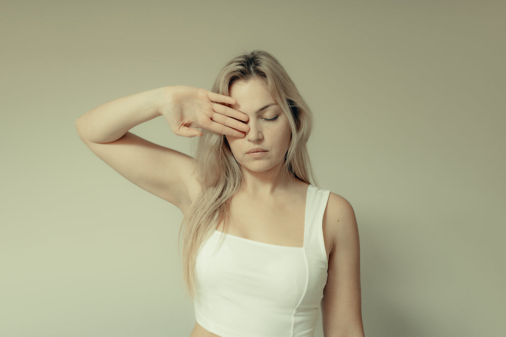 woman holds her arm up and covers her left eye