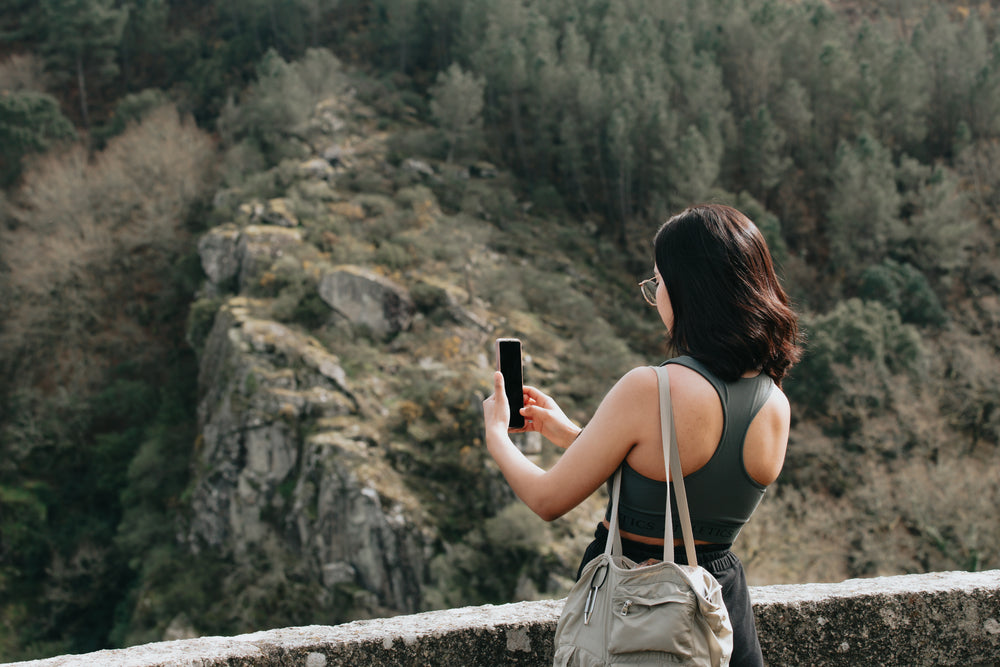 woman holds her cellphone out to take a picture outdoors