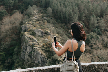 woman holds her cellphone out to take a picture outdoors