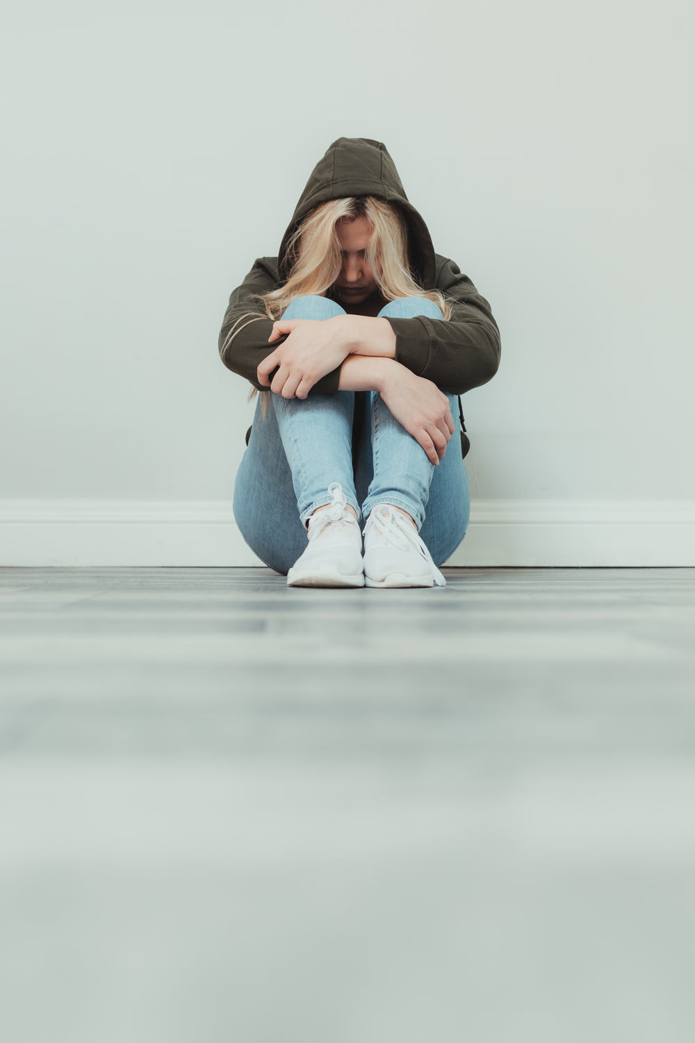 woman holds her legs and looks down at ground