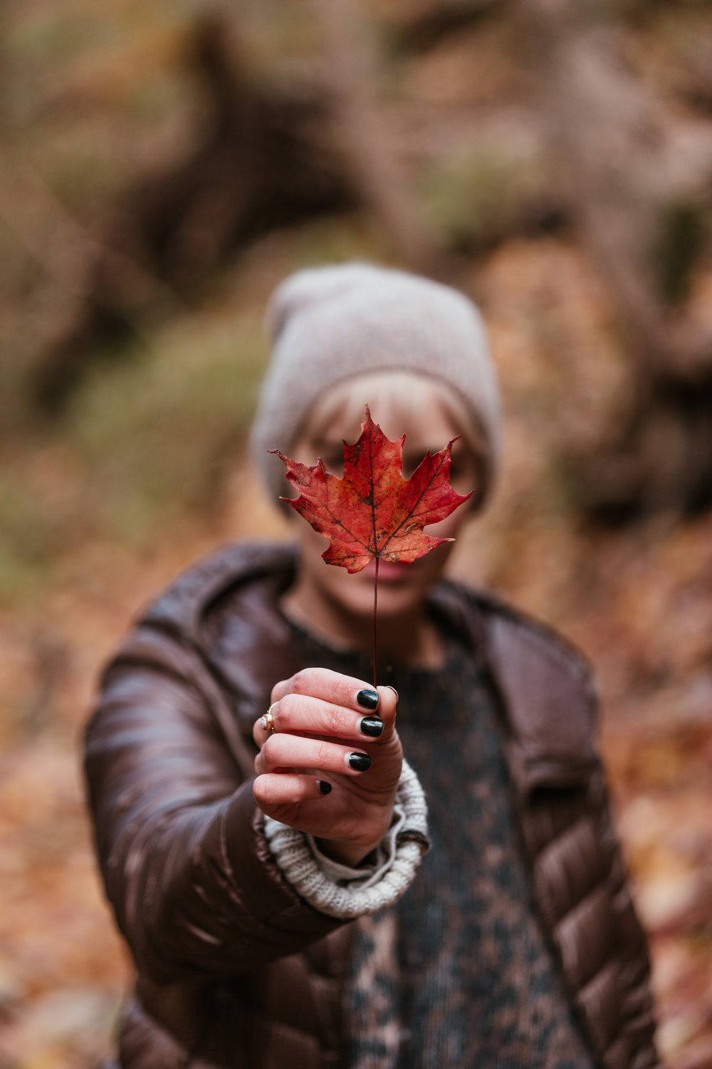 woman holds maple leaf in fall