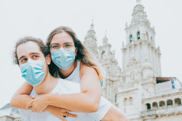 woman hugs man while wearing blue facemask