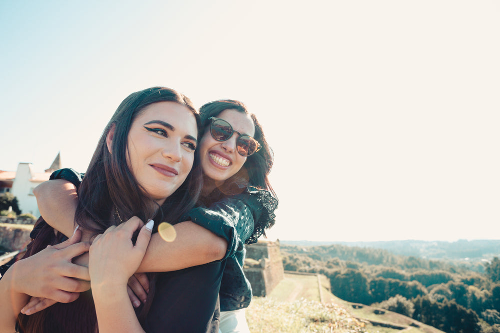 woman hugs other woman from behind